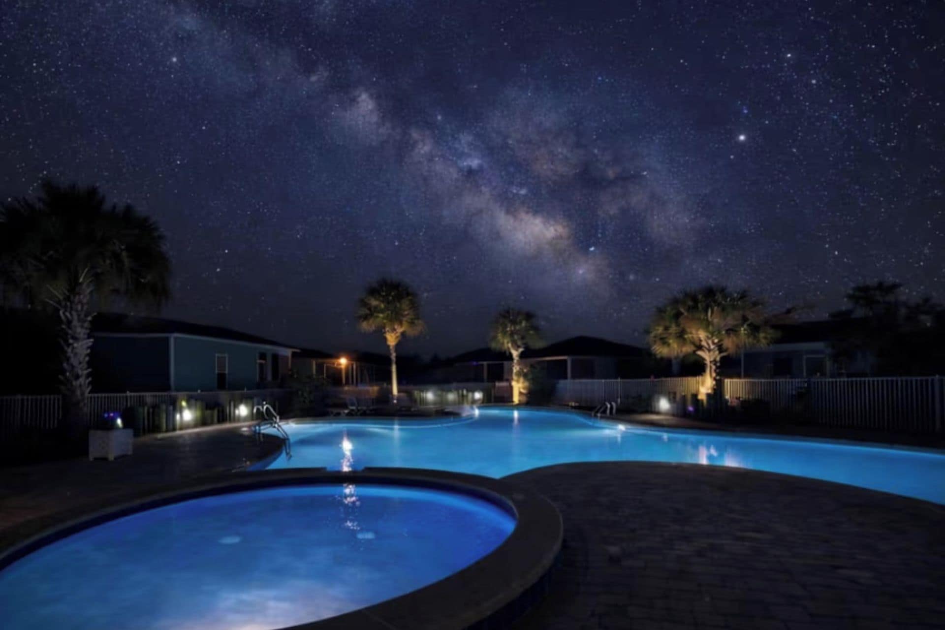 Ein Schwimmbecken bei Nacht mit Sternenhimmel und sichtbarer Milchstraße.