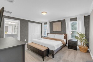 A bedroom with a bed, bedside tables, a bench, a window with curtains, and a wall-mounted artwork. - Renovated 4 BDR With pvt Pool (Kissimmee)