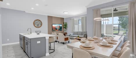 A modern kitchen with a dining area, a large window, and a view of the outdoors.