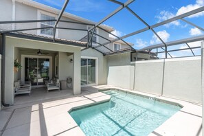 A swimming pool with a glass enclosure, a patio area with seating, and a view of a residential building. - Renovated 4 BDR With pvt Pool (Kissimmee)
