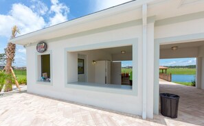 A building with a covered outdoor area, a sign with a logo, and a view of a body of water. - Renovated 4 BDR With pvt Pool (Kissimmee)