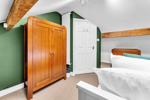 A bedroom with a wooden wardrobe, a white door, a bed with white bedding, and green walls. - Spacious Stoke Townhouse 3Br Near Hospital (Stoke-on-Trent)