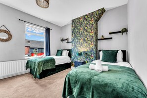A bedroom with two beds, a window, a wall-mounted lamp, and a view of the outside. - Spacious Stoke Townhouse 3Br Near Hospital (Stoke-on-Trent)