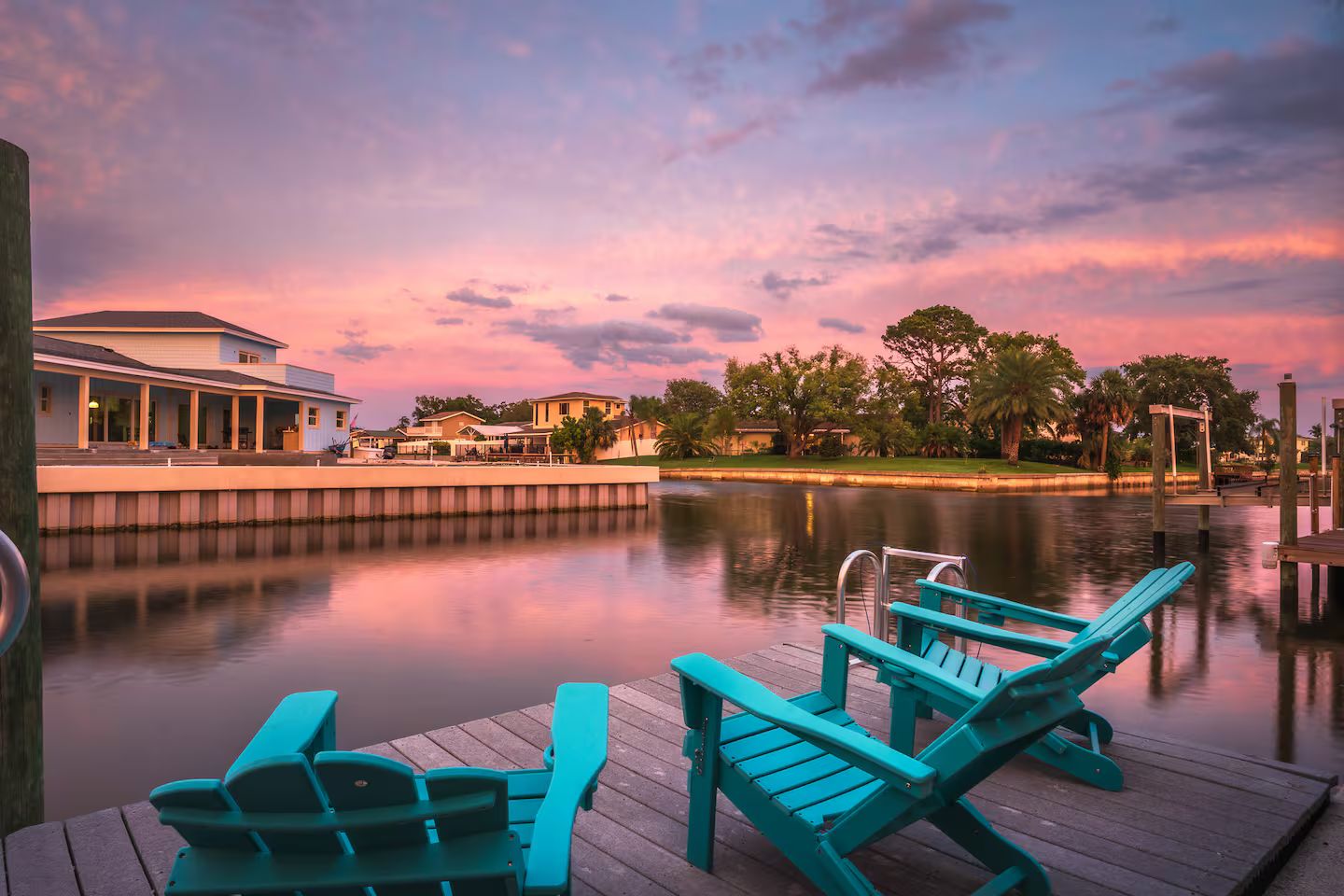 A waterfront property with a dock, a row of chairs, and a building with columns.