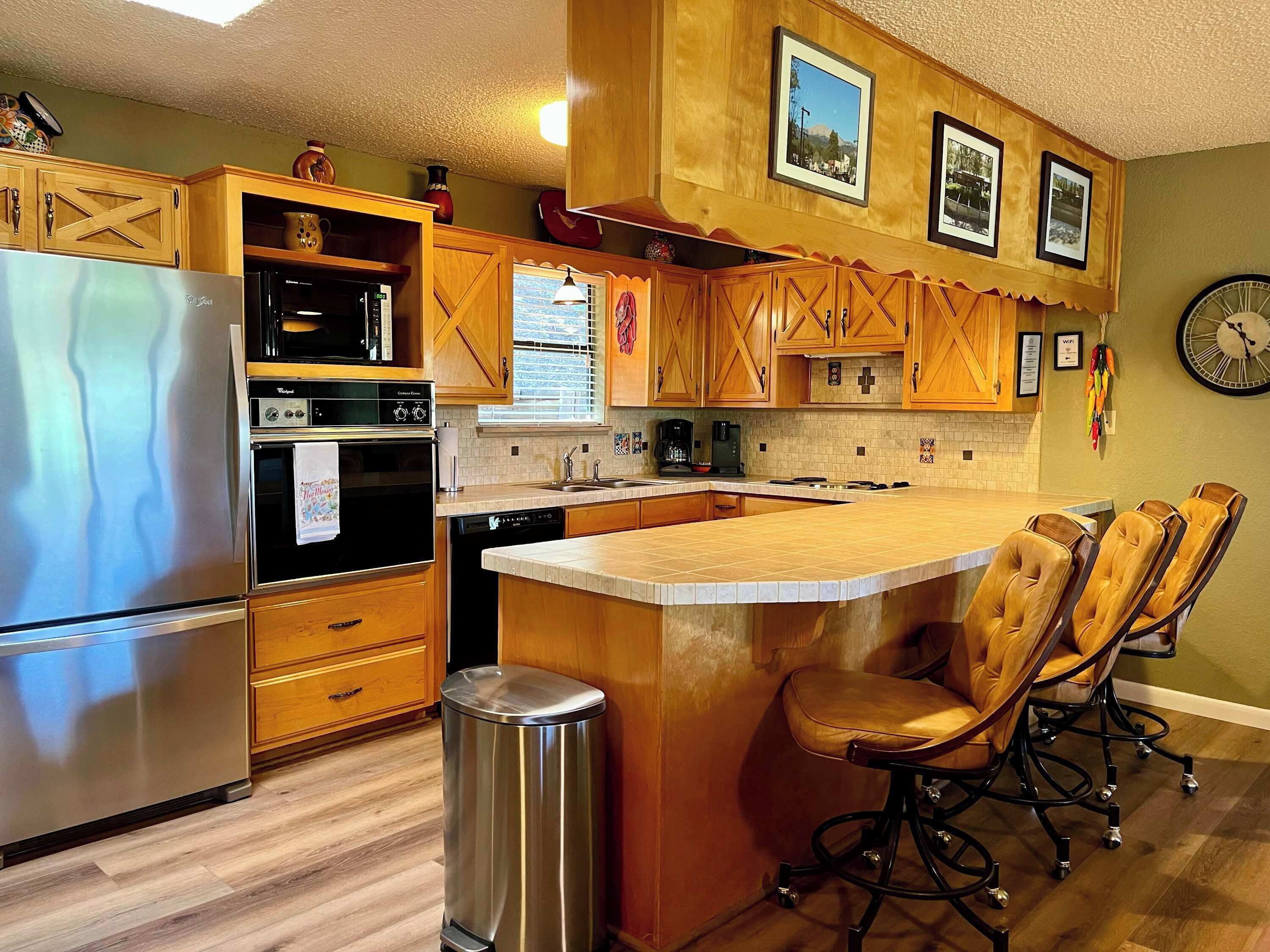 A kitchen with wooden cabinets, stainless steel appliances, and a central island with chairs.