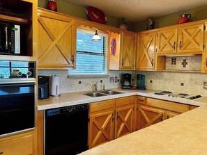 A kitchen with wooden cabinets, a dishwasher, a stove, a sink, and a window with blinds. - Groovy View Cabin- Mountain Views W Covered Porch - Pet Friendly (Ruidoso)