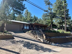 A building with a covered porch, a garage, and a staircase leading to a second level. - Groovy View Cabin- Mountain Views W Covered Porch - Pet Friendly (Ruidoso)