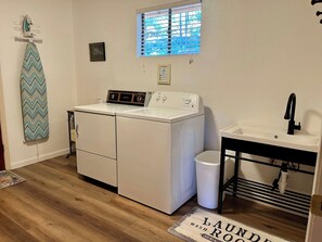 A laundry room with a washer and dryer, a window with blinds, a sink, and a trash can. - Groovy View Cabin- Mountain Views W Covered Porch - Pet Friendly (Ruidoso)