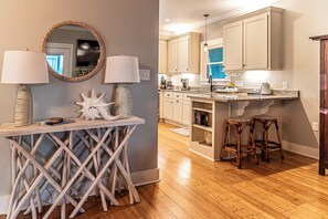 A kitchen with wooden flooring, a bar area with stools, and a dining table with two lamps. - 4005 Rookery 3 Sea Story two pools close to beach (Gulf Shores)