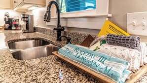 A kitchen with granite countertops, a stainless steel sink, and a window with blinds. - 4005 Rookery 3 Sea Story (Gulf Shores)