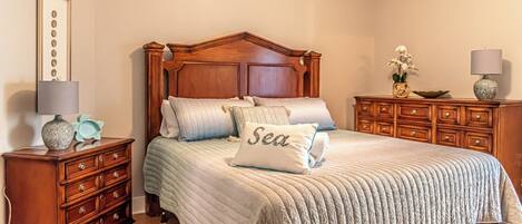 A bedroom with a wooden bed, a nightstand, a dresser, and a lamp.