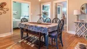 A dining area with a table set for four, surrounded by chairs, and a bench. - 4005 Rookery 3 Sea Story (Gulf Shores)