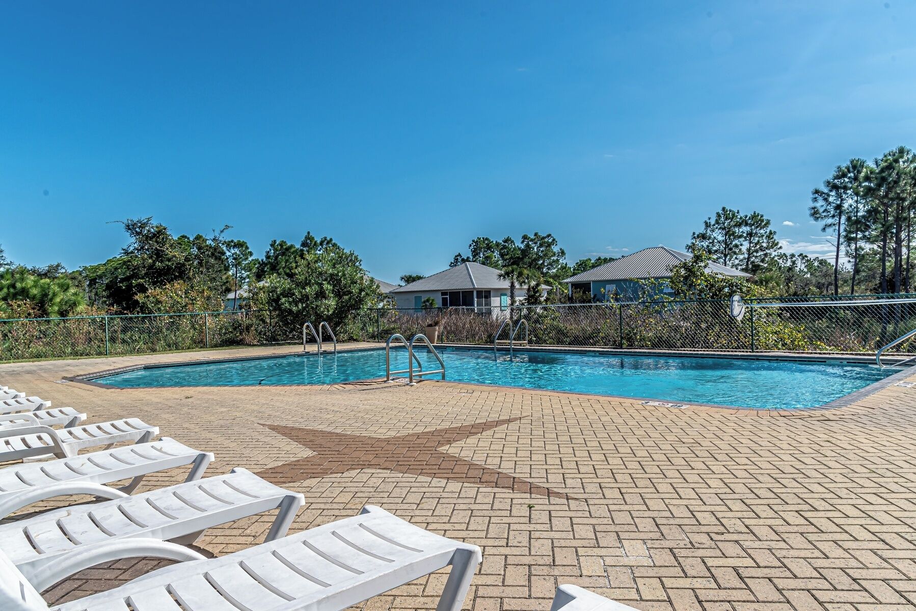 A swimming pool with lounge chairs and a paved deck.