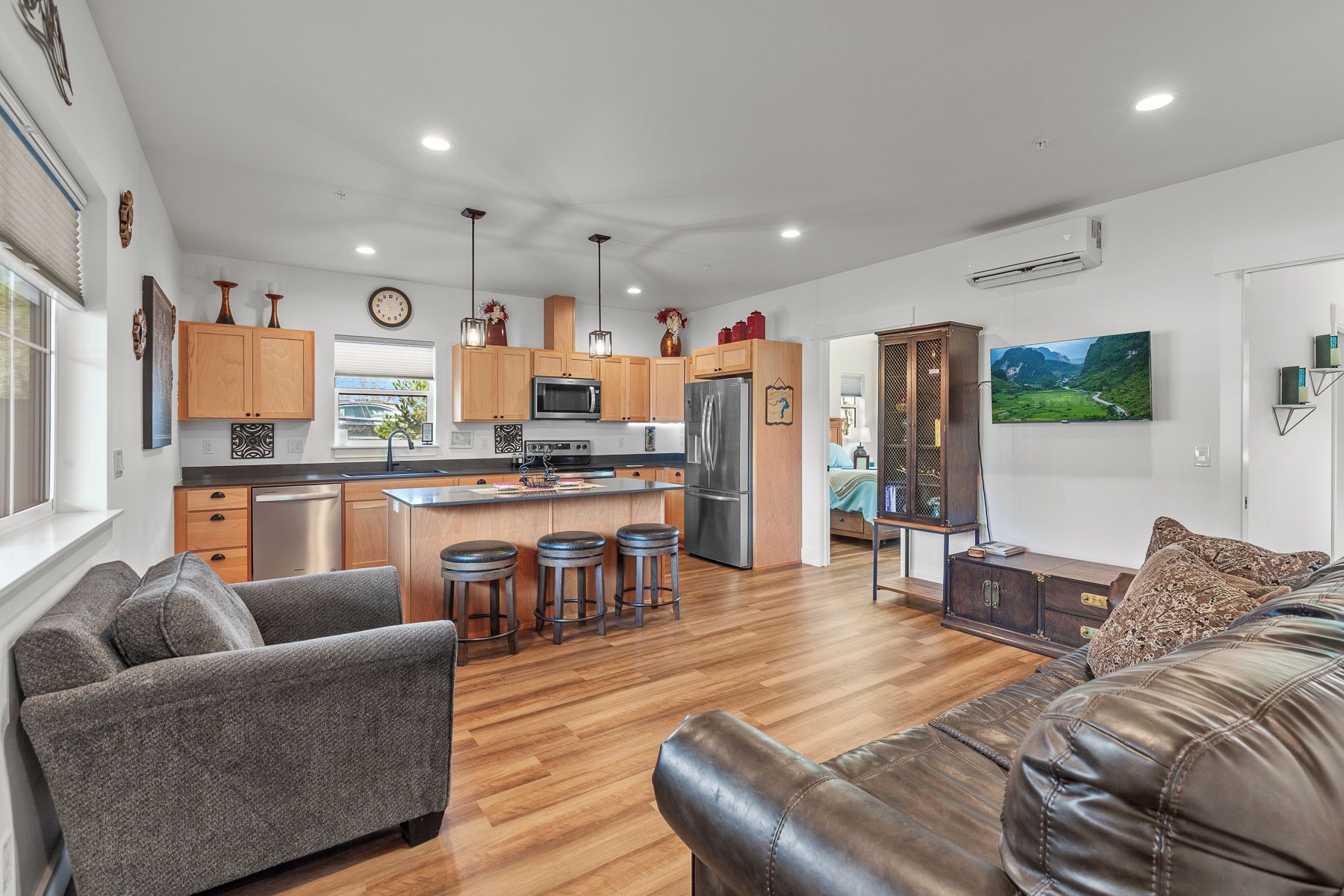 A modern kitchen with wooden cabinets, stainless steel appliances, and a central island with stools.