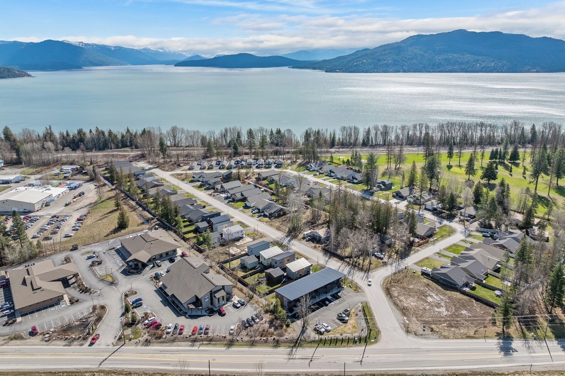 A residential area with houses, a parking lot, and a body of water in the background.