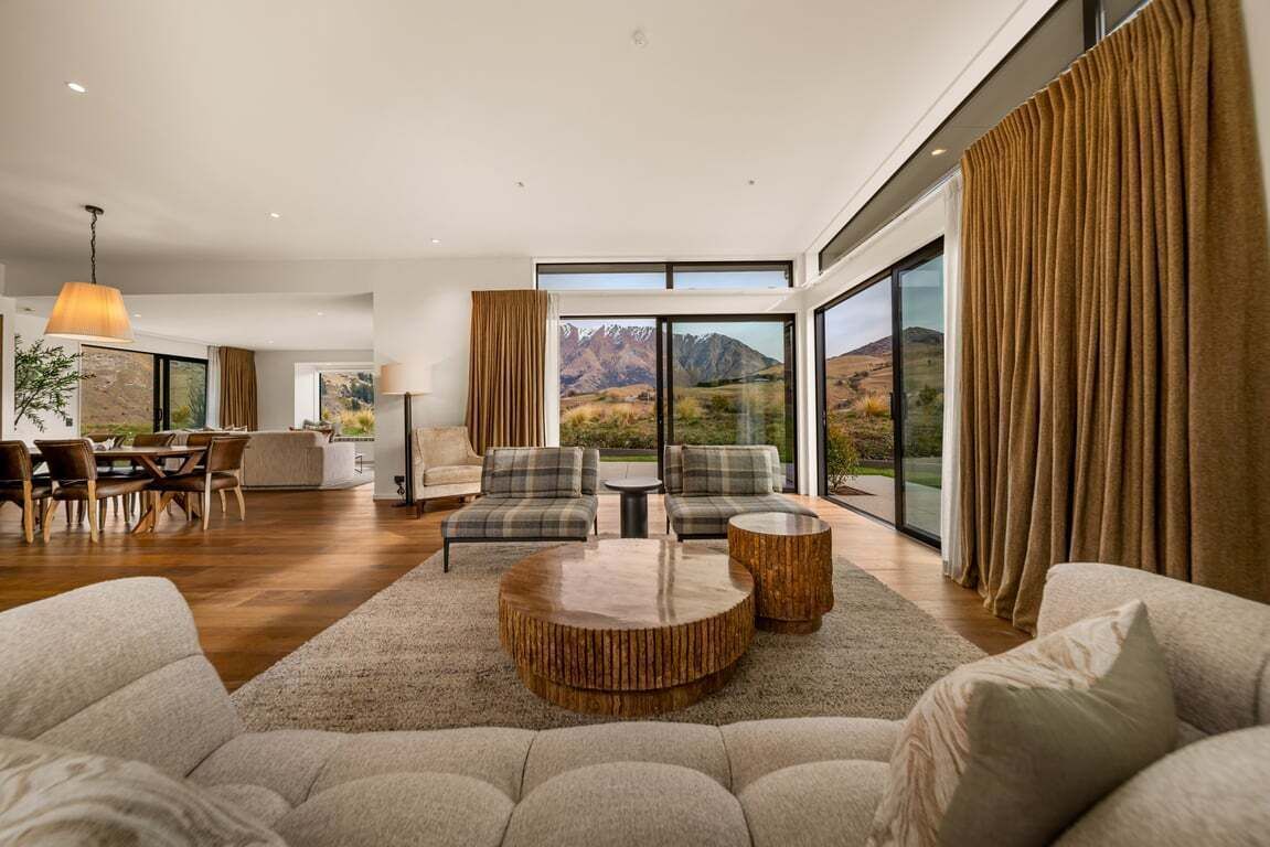 A spacious living area with a large window, a dining set, and a seating arrangement.
