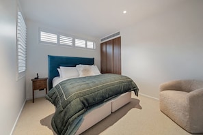 A bedroom with a bed, bedside table, and a chair. - Villa Frogmore (Queenstown)