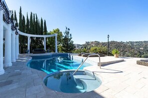Ein Swimmingpool mit einer Pergola und Blick auf eine hügelige Landschaft.