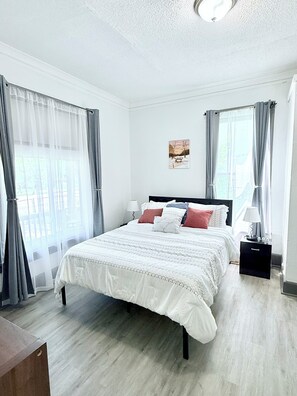 A bedroom with a bed, bedside tables, and curtains.