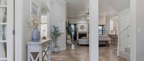 A spacious living area with a fireplace, a dining area, and a kitchen visible in the background.