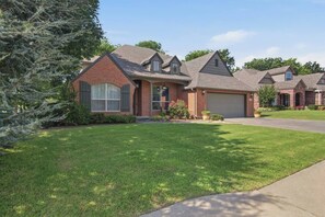 A residential house with a brick facade, a garage, and a well-maintained lawn.