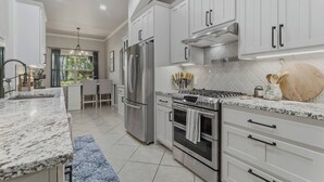 A modern kitchen with white cabinetry, stainless steel appliances, and a granite countertop. - Spacious Bixby Home w/ Fire Pit & Sleeps 12+ (Bixby)