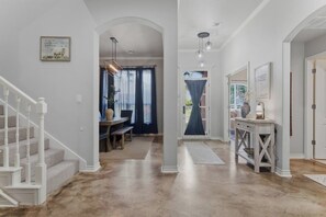 Un pasillo con una escalera, un comedor y una consola con una lámpara.