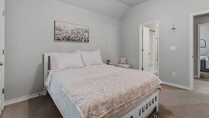A bedroom with a bed, a nightstand, a wall-mounted picture, and a ceiling fan. - Spacious Bixby Home w/ Fire Pit & Sleeps 12+ (Bixby)