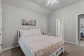Ein Schlafzimmer mit einem Bett, einem Nachttisch, einem Wandbild und einem Deckenventilator.