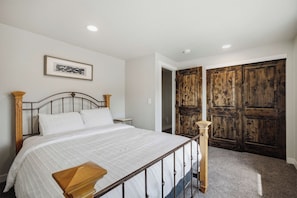 A bedroom with a bed, a wooden headboard, a small bedside table, a framed picture on the wall, and a wooden wardrobe. - Dixon Cove Lookout Near Horsetooth Res (Fort Collins)
