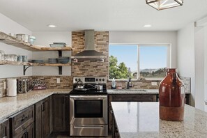 A modern kitchen with a central island, stainless steel appliances, and a brick backsplash. - Dixon Cove Lookout Near Horsetooth Res (Fort Collins)