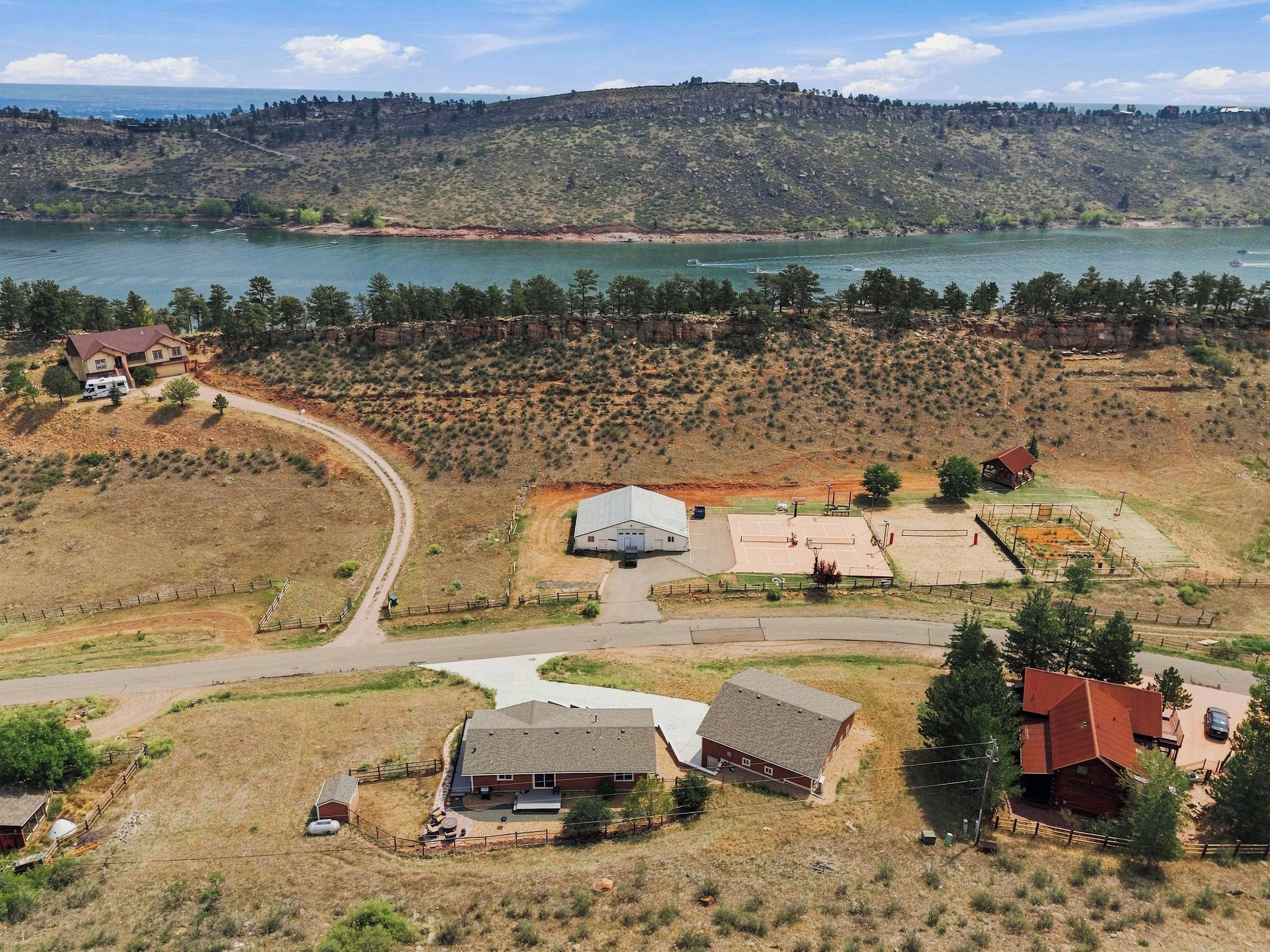 A residential area with houses, a basketball court, and a lake in the background.