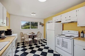 Une cuisine compacte avec un sol à carreaux noirs et blancs, des placards blancs, une cuisinière et un réfrigérateur.