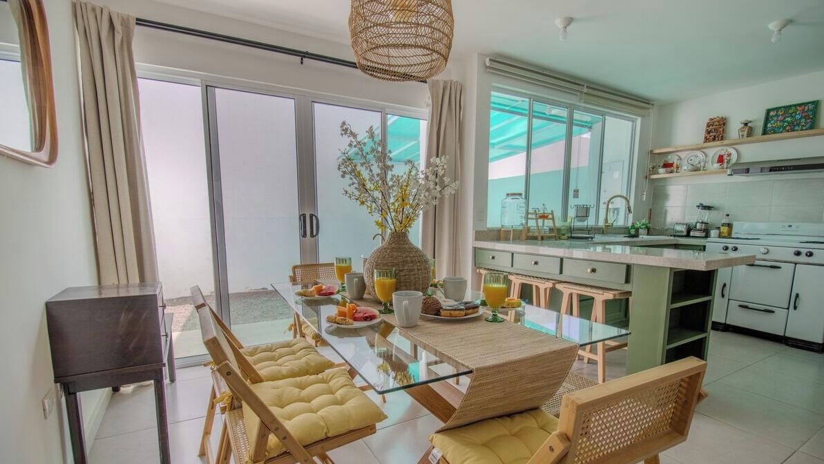 A modern kitchen with a dining area, large windows, and a view of the outdoors.