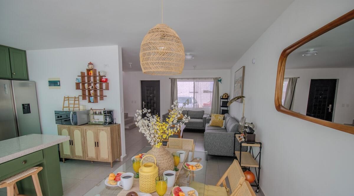 A modern kitchen with a refrigerator, wooden cabinets, and a dining area with a table set for two.