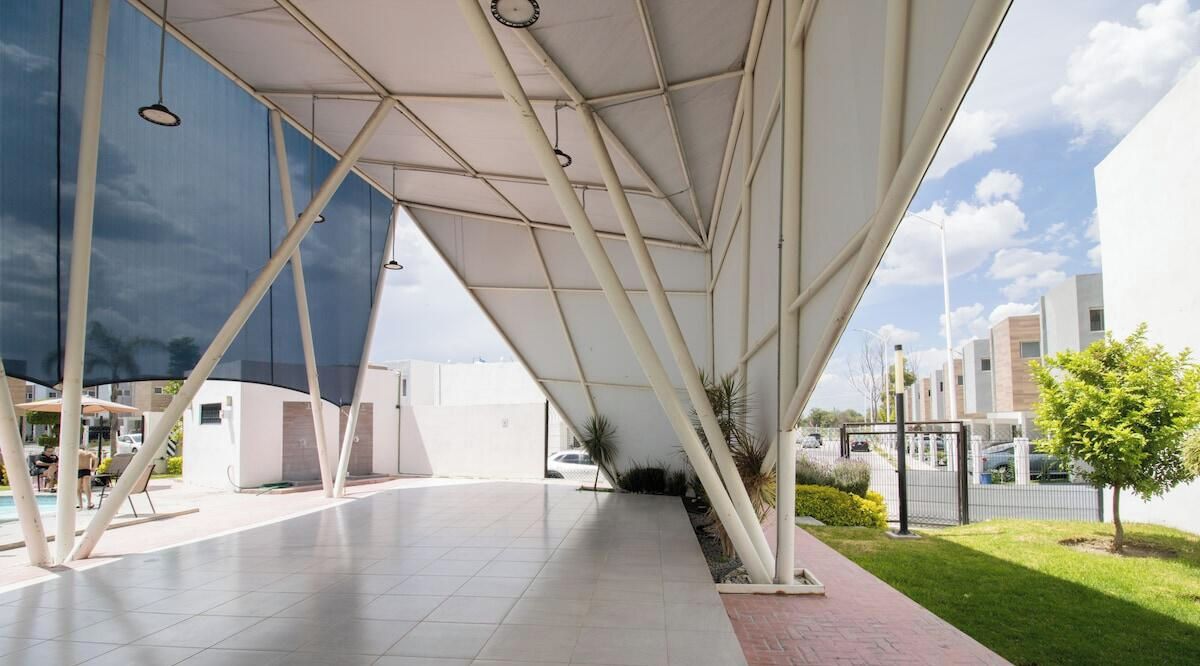 An outdoor area with a modern architectural design, featuring a covered walkway and a view of the surrounding buildings.