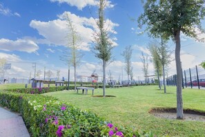 A park with benches, trees, and a clear sky.