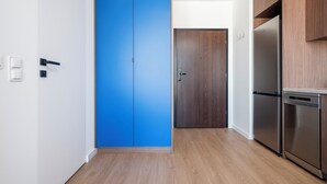 A modern kitchen with a blue door, wooden cabinets, and stainless steel appliances.