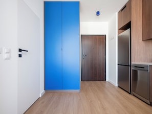 A modern kitchen with a blue door, wooden cabinets, and stainless steel appliances.