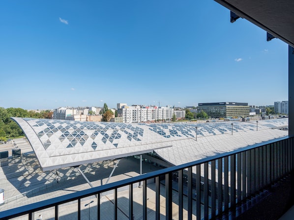 A modern building with a unique geometric roof design, a clear sky, and a view of surrounding urban buildings.