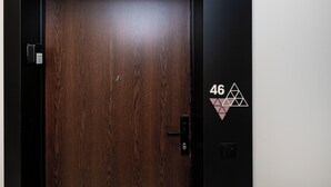 A wooden door with a digital lock and a keypad, and a wall with the number '46' and a geometric design.