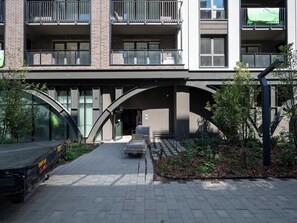 A modern building with a covered entrance, a truck parked outside, and a small garden area. - Łódź Fabryczna Modern Studio (Łódź)