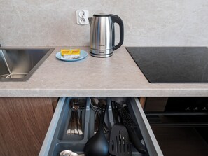 A kitchen with a kettle, a plate with food packets, and a drawer with utensils. - Łódź Fabryczna Modern Studio (Łódź)