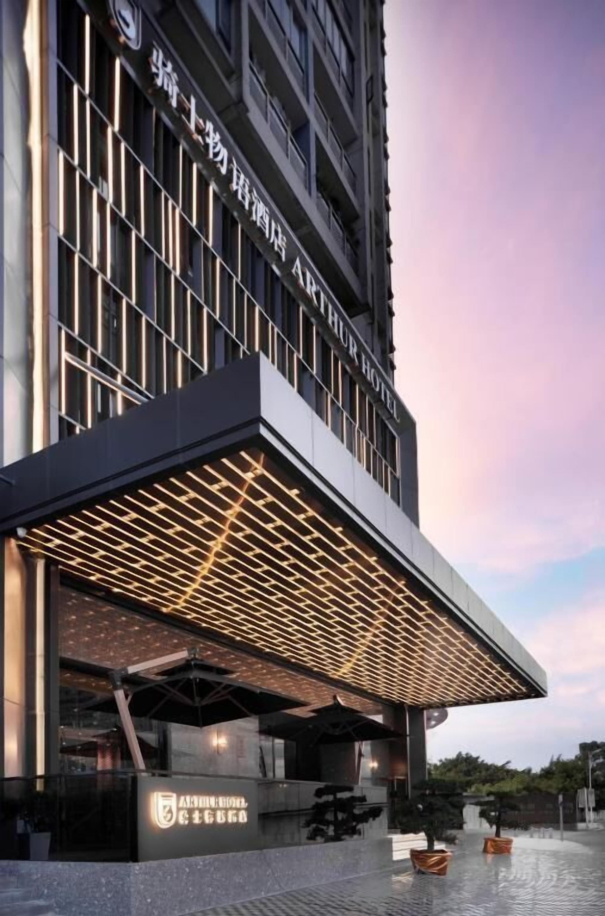A modern hotel entrance with a prominent overhang and illuminated signage.