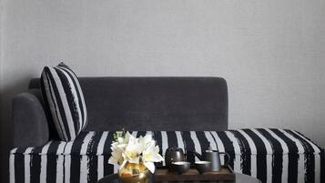 Una sala moderna con un sofá, una mesa de centro redonda de vidrio y un jarrón decorativo con flores.