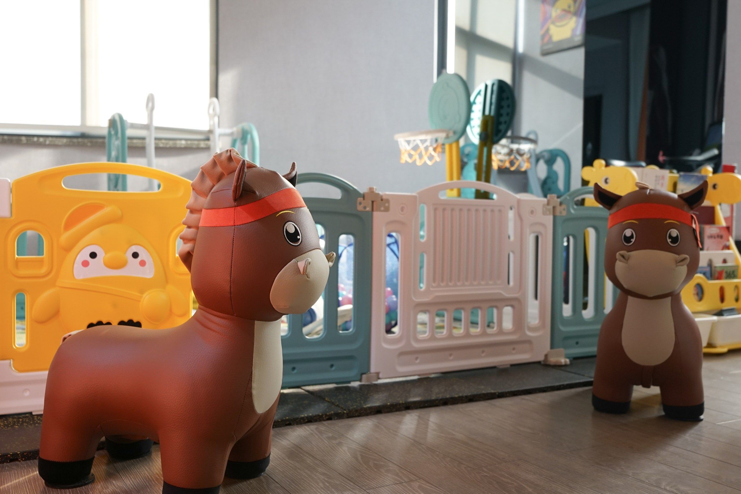 Two toy horses and a yellow toy car in a play area.