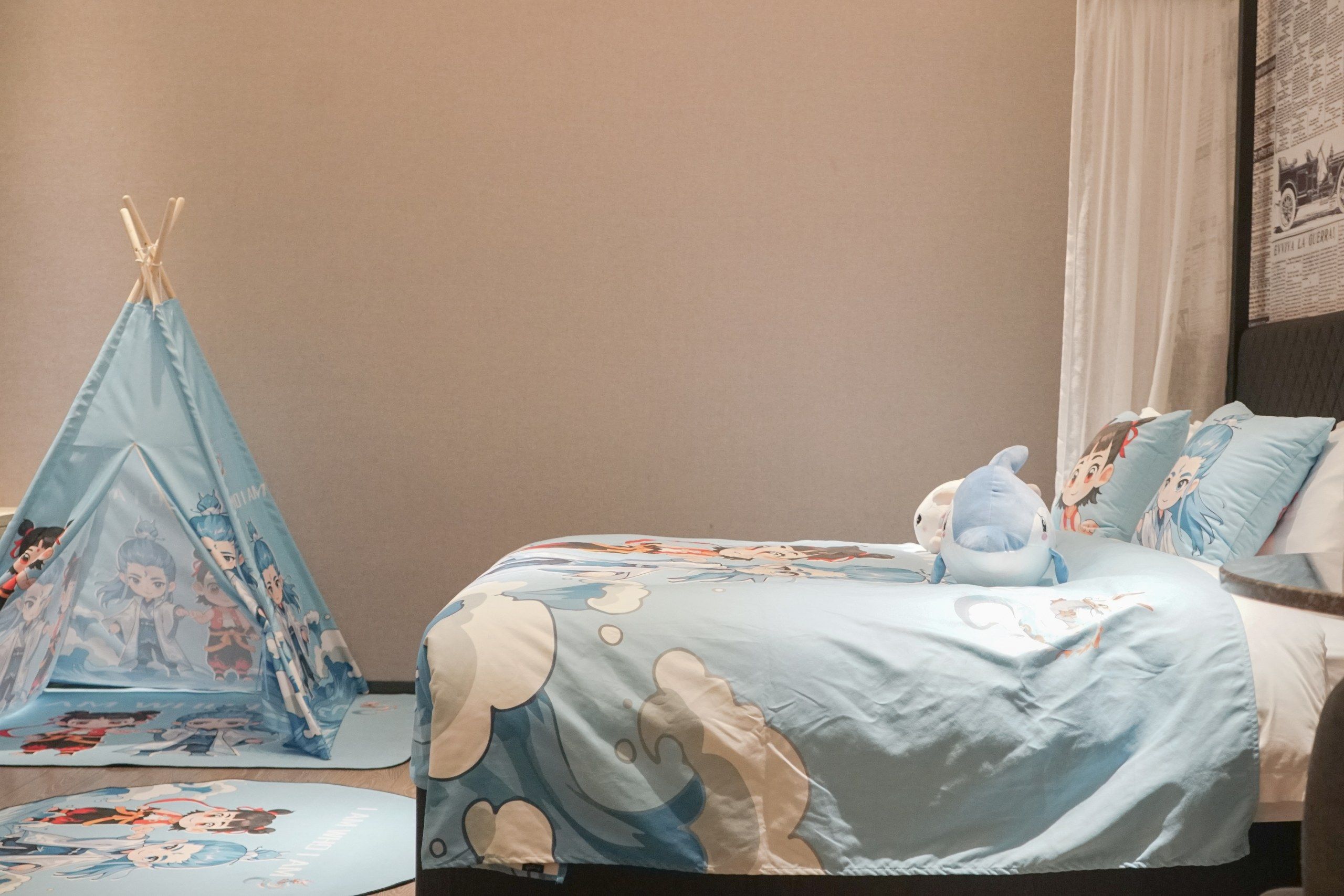 Un dormitorio con cama, almohadas, una colcha azul, un tipi azul y una pared con un periódico.
