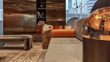 Een modern interieur met een bank, een decoratieve steen, een boekenplank en een uitzicht op de stad door grote ramen.