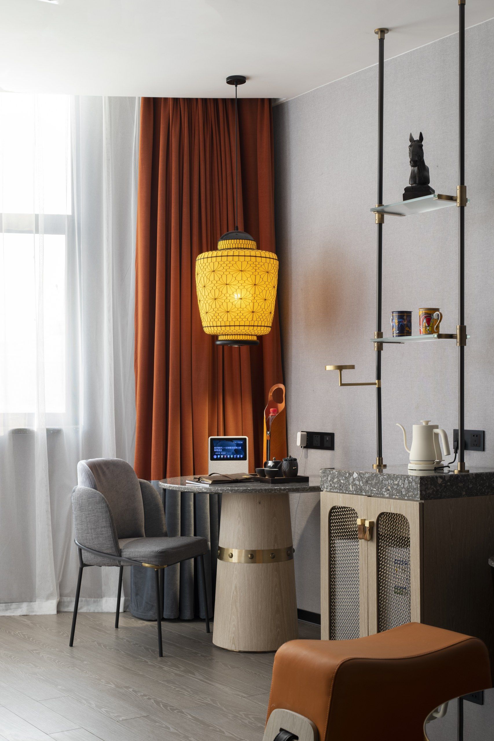 Een moderne hotelkamer met een bureau, stoel en een opvallende gele hanglamp.