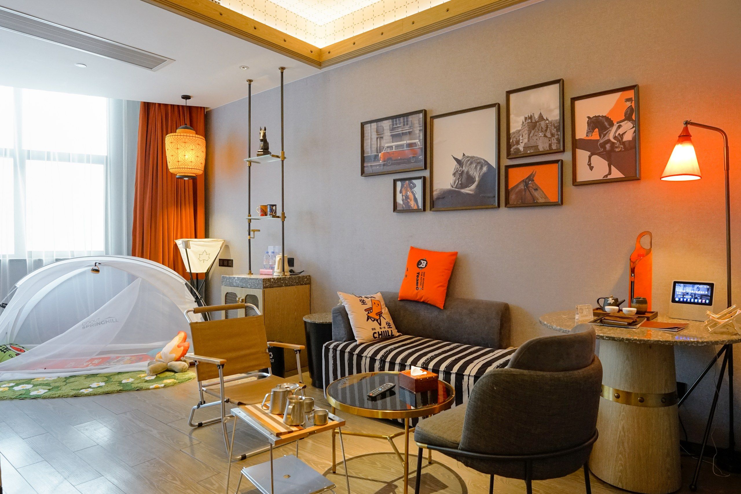 Ein modernes Wohnzimmer mit Sofa, Sesseln, Couchtisch und einer zeltartigen Struktur.
